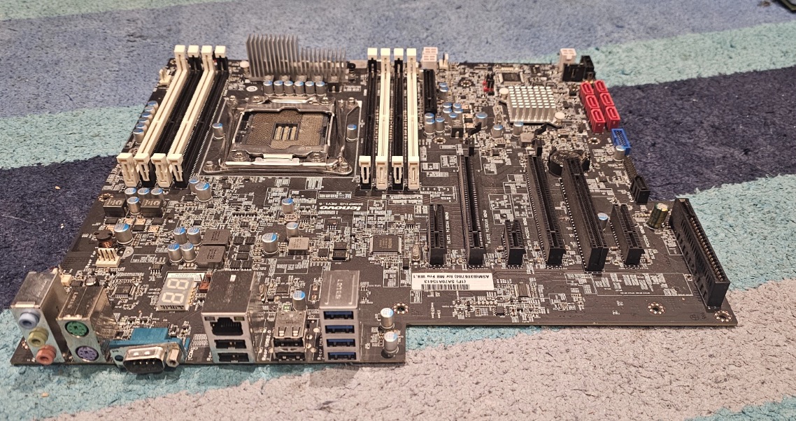 Desktop PC motherboard laid out showing all components, RAM slots, PCIe slots, and connection ports during diagnostic inspection