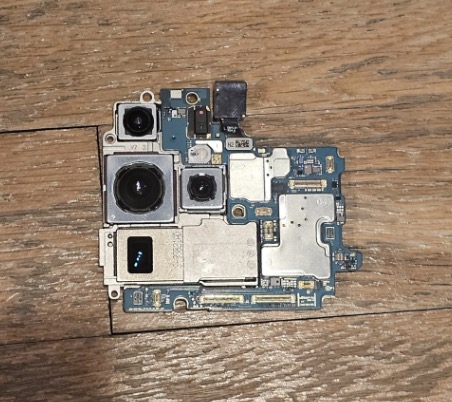 Samsung Galaxy S23 Ultra motherboard removed and laid out showing camera modules, chips, and micro-components for repair
